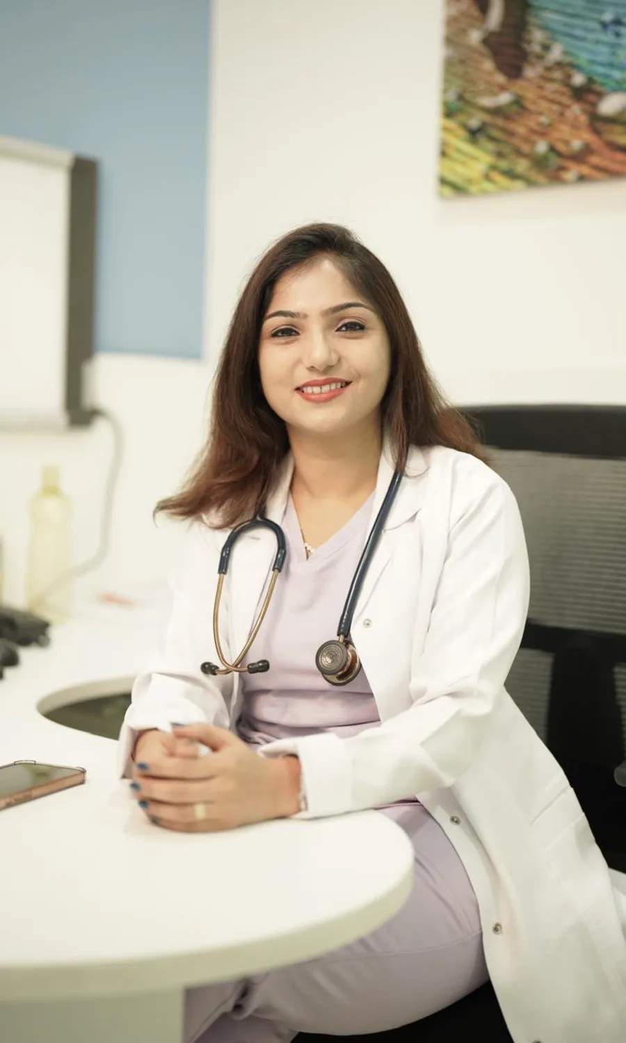 Dr. Rashmi Bhamare at her consulting room desk, wearing a stethoscope