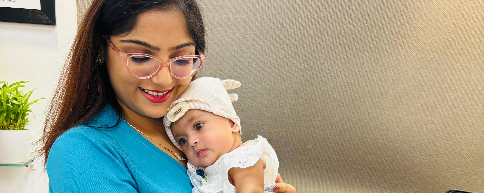 Dr. Rashmi Bhamare in scrubs, smiling at a baby she is holding
